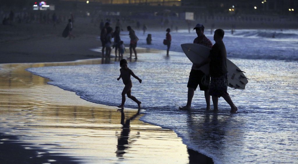 Algunos bañistas disfrutan al atardecer en la playa de la Zurriola de San Sebastián